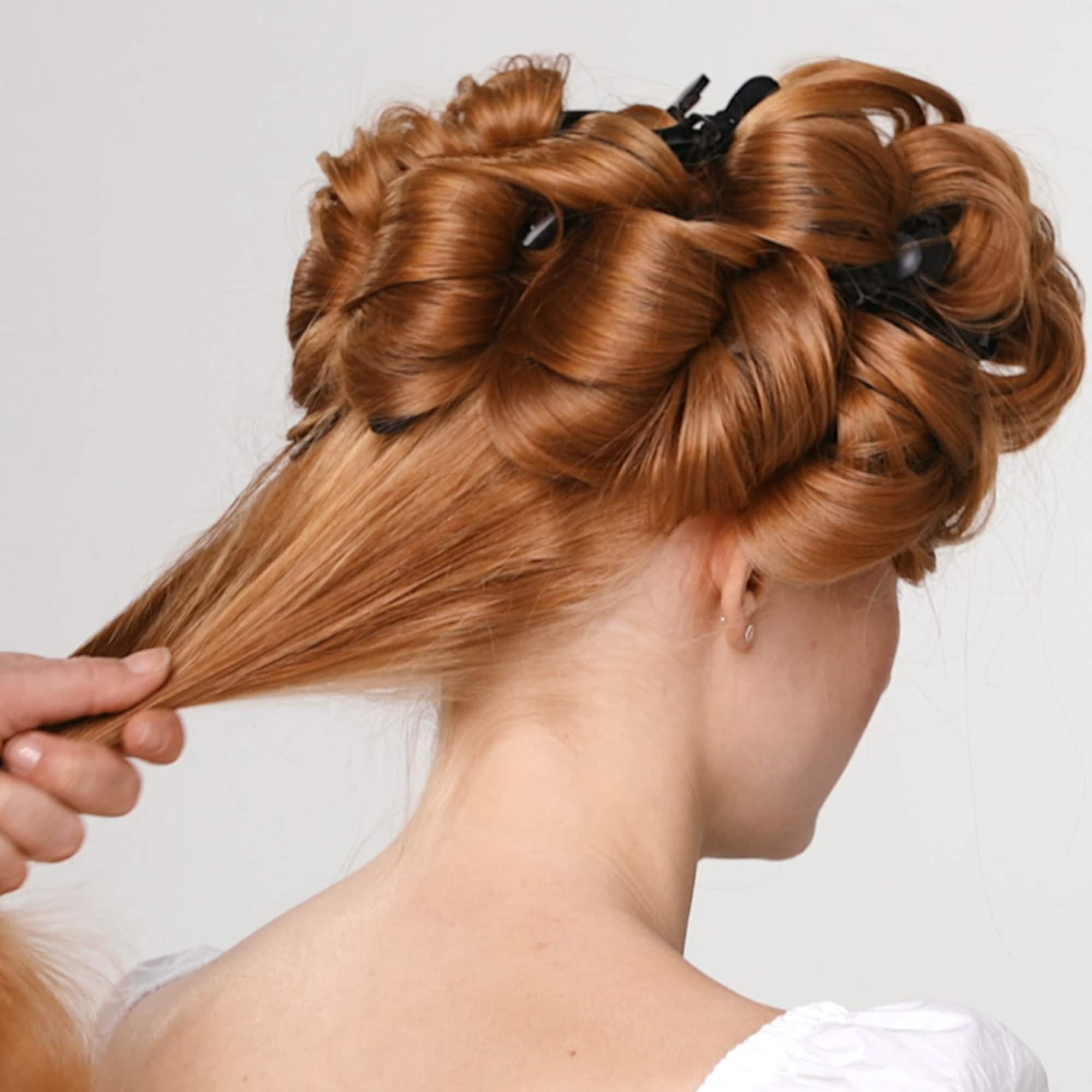Seksjonering av håret til en kvinne med rødt hår og en hånd som holder en del av det bakre håret 