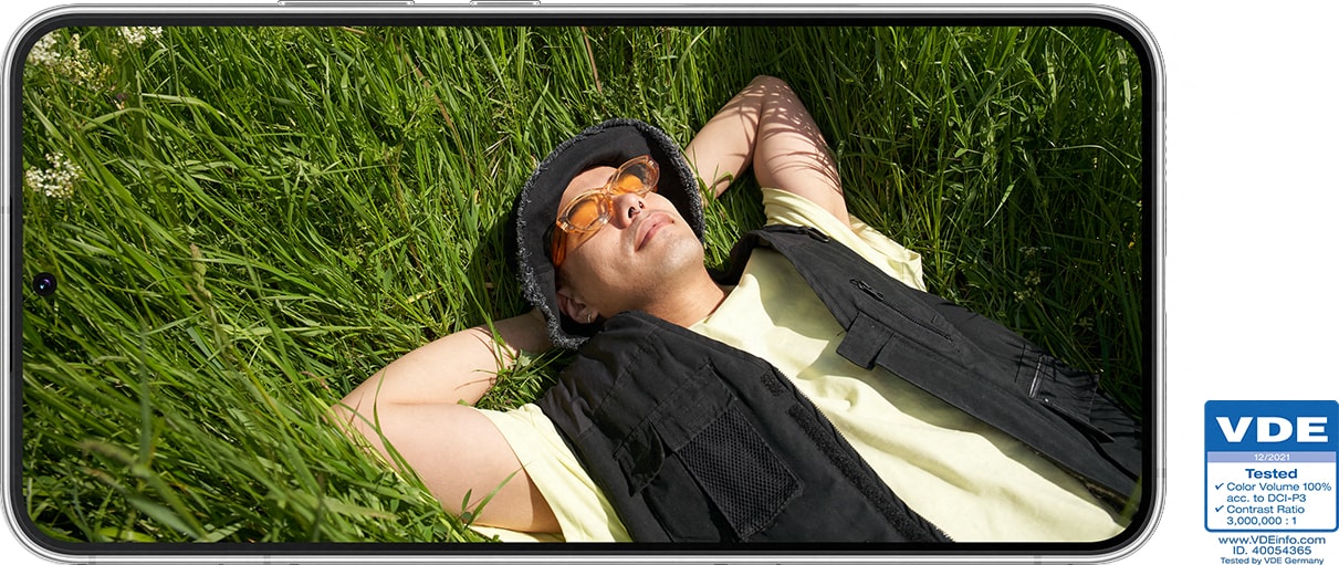 Samsung Galaxy S22 i landskapsmodus, med bilde av ung mann liggende i gress
