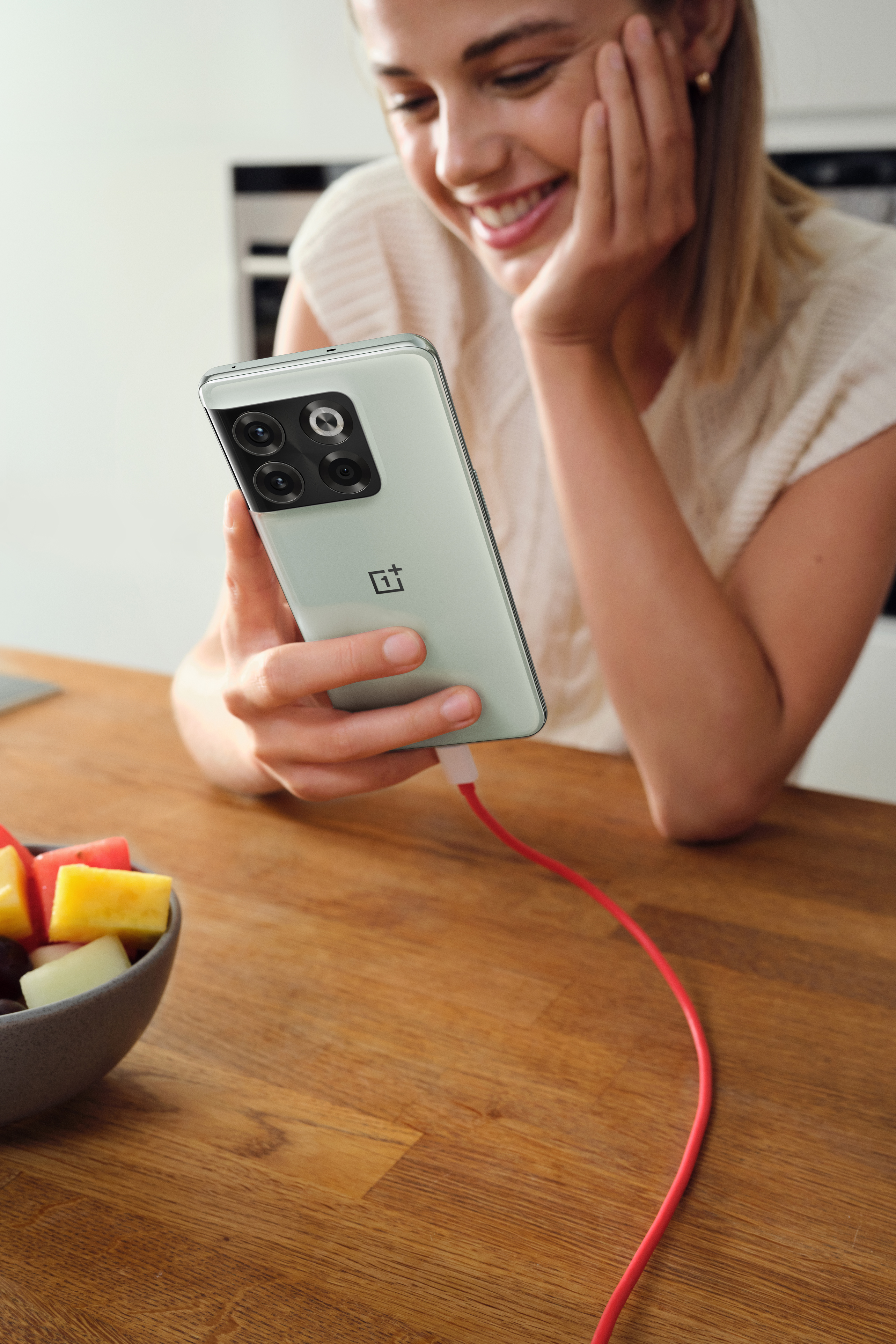 Smilende jente lader OnePLus 10T-telefonen sin