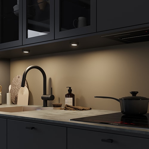 A black kitchen with kitchen light in the top cabinets