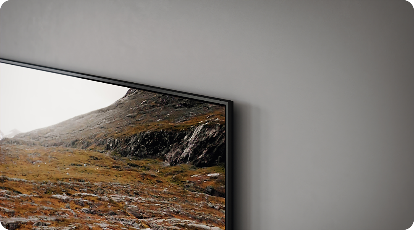 Nærbilde av et Samsung Q60C TV-hjørne på en grå vegg