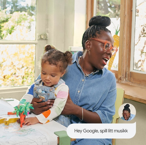 Kvinne som ber Google-assistenten spille litt musikk på Google Pixel Tablet mens hun har en ung jente på fanget