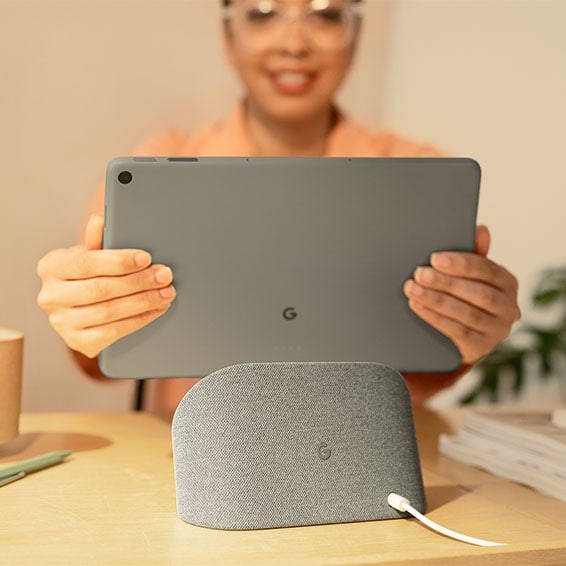 Google Pixel Tablet blir plassert i ladestasjonen av en kvinne