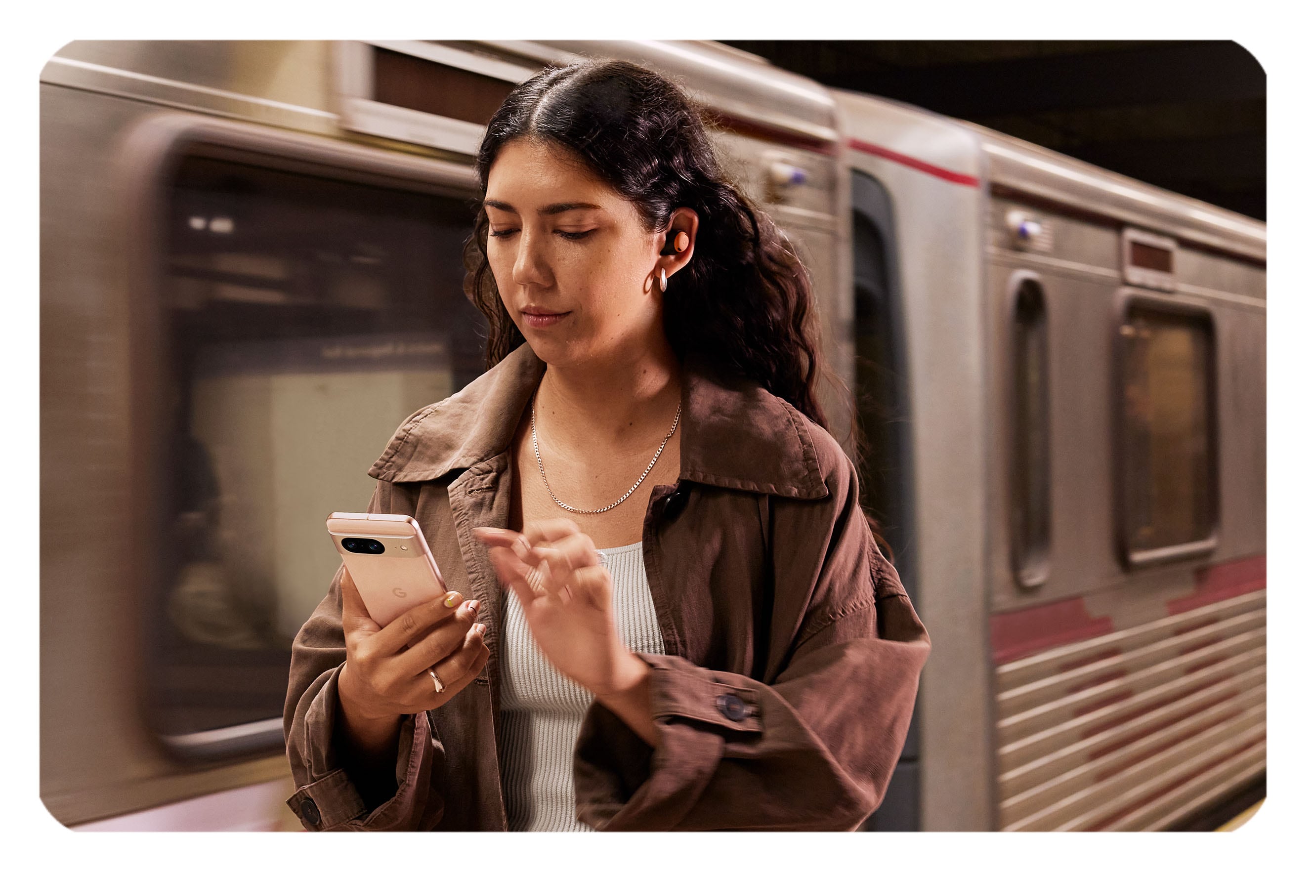 Young woman holding Pixel 8 with a subway in the background