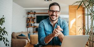 Smilende mann foran PC-en