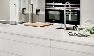 hvitt kjøkken med integrerte hvitevarer, industriell vask og vinskap