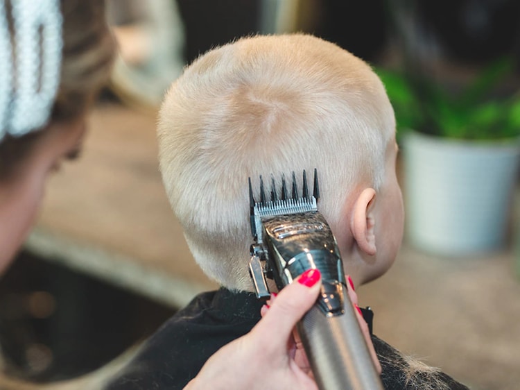 kvinne klipper gutts hår i nakken med hårklippemaskin
