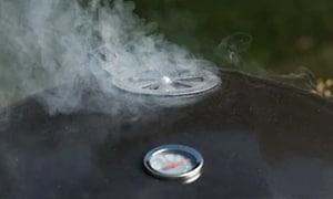 røyk kommer ut fra toppen av en kullgrill