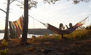 to barn sitter i hengekøye med havutsikt en sommerdag