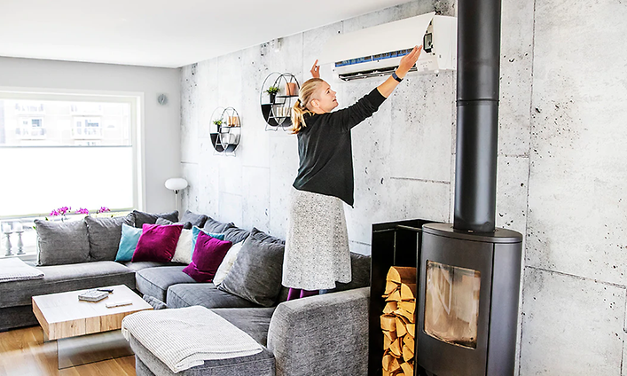 kvinne i stue står i sofa for å undersøke filter på varmepumpe