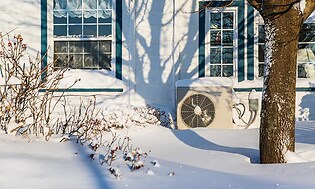 varmepumpe på utside av hus i snø