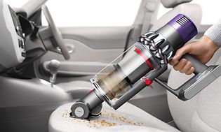 Person som bruker Dyson V10-støvsuger i bil