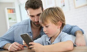 gutt og mann ser på smarttelefon sammen