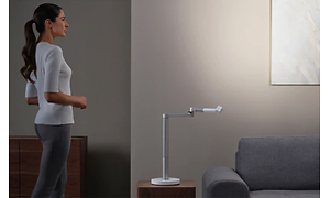 Kvinne som står ved Dyson Lightcycle Morph skrivebordslampe