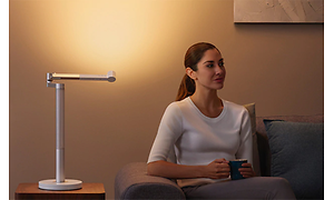Kvinne som sitter ved Dyson Lightcycle Morph skrivebordslampe
