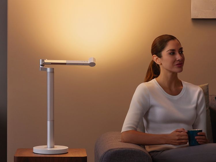 Dyson Lightcycle bordlampe som lyser opp en vegg