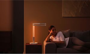 Kvinne som slapper av på en sofa med en Dyson Lightcycle Morph på et bord
