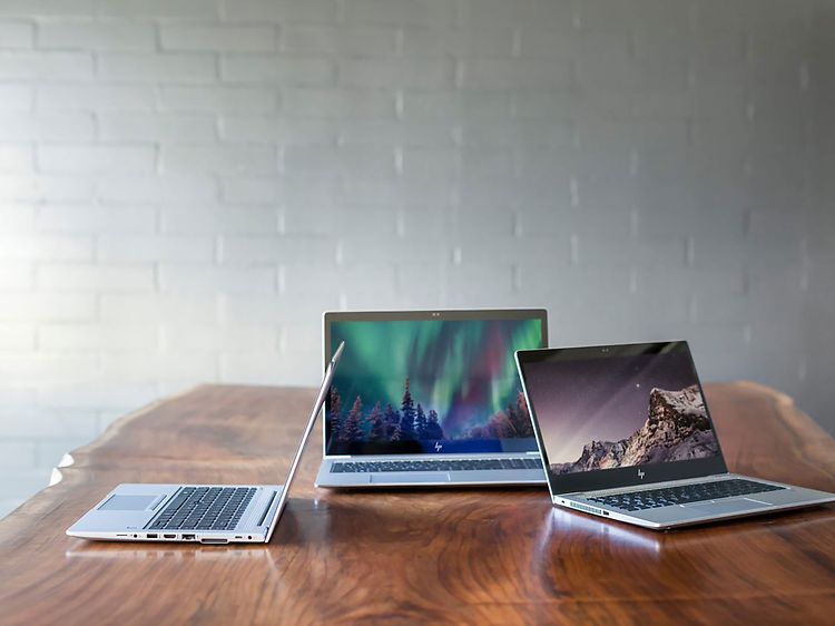 Tre laptoper stående på pult