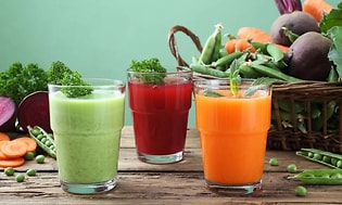 ulike typer juice på et bord med grønnsaker