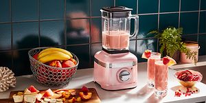 rosa KitchenAid-blender på kjøkkenbenk med frukt og smoothier