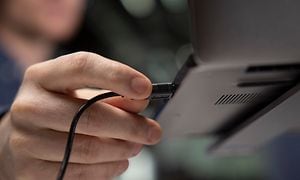 Hånd som kobler Konftel Cam10 til en bærbar PC