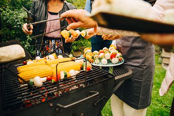 Mennesker som står rundt en kullgrill og lager mat