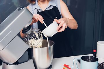 En dame lager en kake med en kjøkkenmaskin