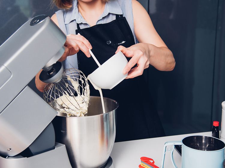 En dame lager en kake med en kjøkkenmaskin