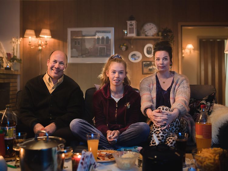 Familie på tre som sitter på en sofa