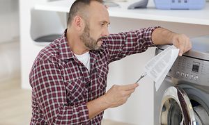 En mann sjekker instruksjonene når han installerer en vaskemaskin
