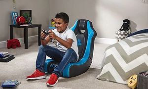 Gutt sitter i en X Rocker-stol og spiller et konsoll-spill