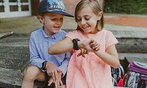 Gutt og jente ser på en Xplora 5 smartklokke på jentas håndledd