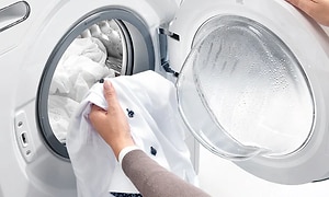 hvite klær tas ut av en vaskemaskin