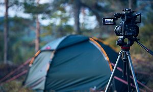 Kamera på stativ peker mot et telt i skogen i bakgrunnen