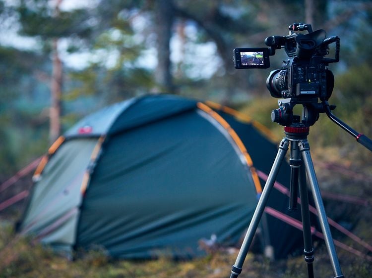 Kamera på stativ peker mot et telt i skogen i bakgrunnen