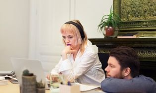 Kvinde og mand kigger på en bærbar computer på et skrivebord