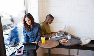 To personer som sitter i en kafé med bærbare PC-er