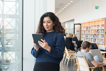 Kvinne som står i bibliotek med nettbrett