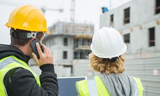 To bygningsarbeidere som bruker nettbrett og mobil