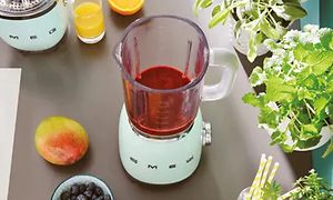 50-tallsstil pastellblå blender fra Smeg med smoothie på en kjøkkenbenk