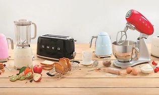 Samling av ulike kjøkkenprodukter fra Smeg i ulike farger på en kjøkkenbenk med matvarer