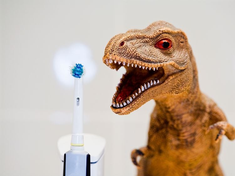 Elektrisk tannbørste ved siden av en lekedinosaur