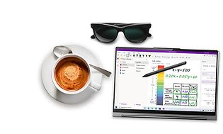 En brettbar PC med en penn ved siden av en kaffekopp og solbriller