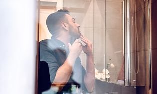 Mann barberer seg foran speilet