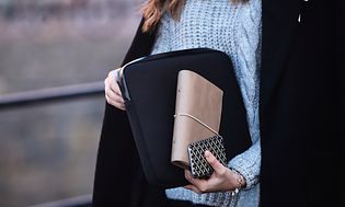 Kvinne bærer PC i etui og notisbok