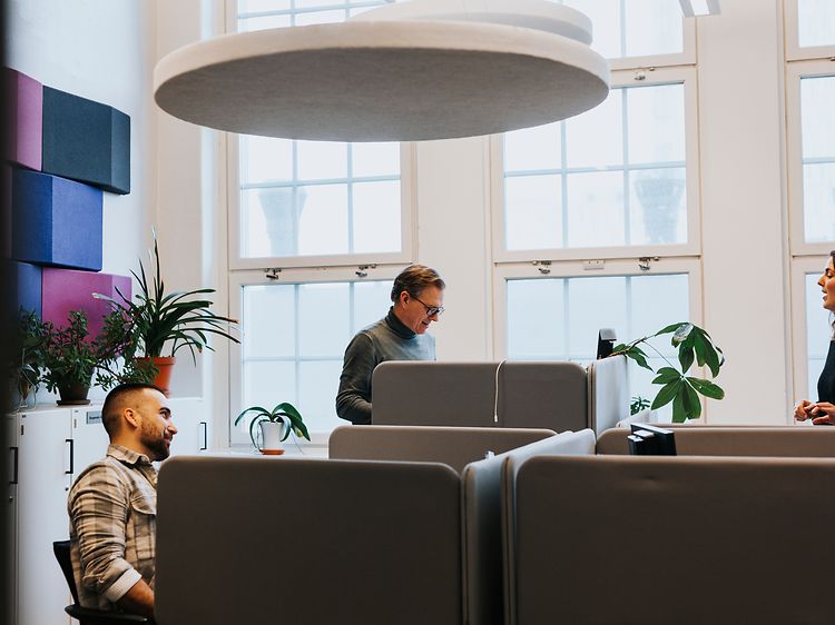 Tre personer i et åpent kontorlandskap