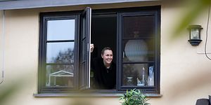 En kvinne åpner et vindu fra avstand