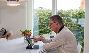 En mann sitter hjemme og jobber på en iPad