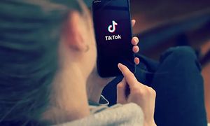 Kvinne holder en smarttelefon med TikTok-logoen på skjermen