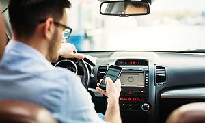 Mann i bil som ser på smarttelefon